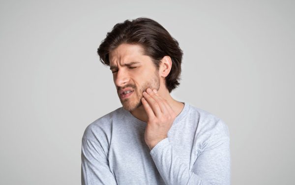 man holding his jaw in pain