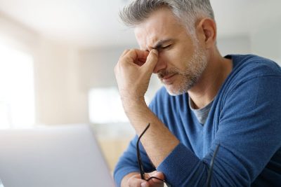 man holding the bridge of his nose with eyes closed while suffering from a migraine tmj headache
