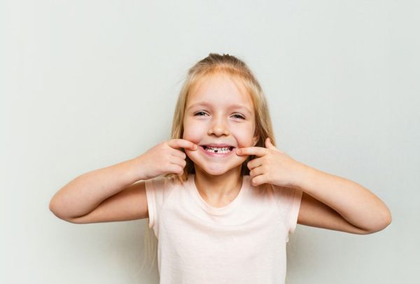 young child smiling and pointing at teeth