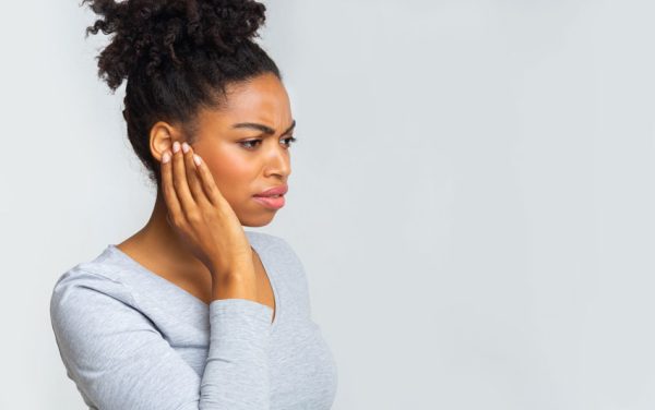 adult woman holding her jaw in discomfort