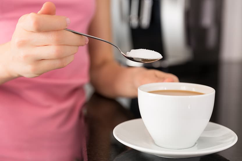Woman adding sugar to the coffee