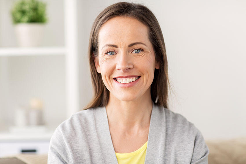 Why-Porcelain-Veneers-Are-the-Most-Popular-Cosmetic-Dental-Procedure beautiful woman relaxing on her couch with a smile