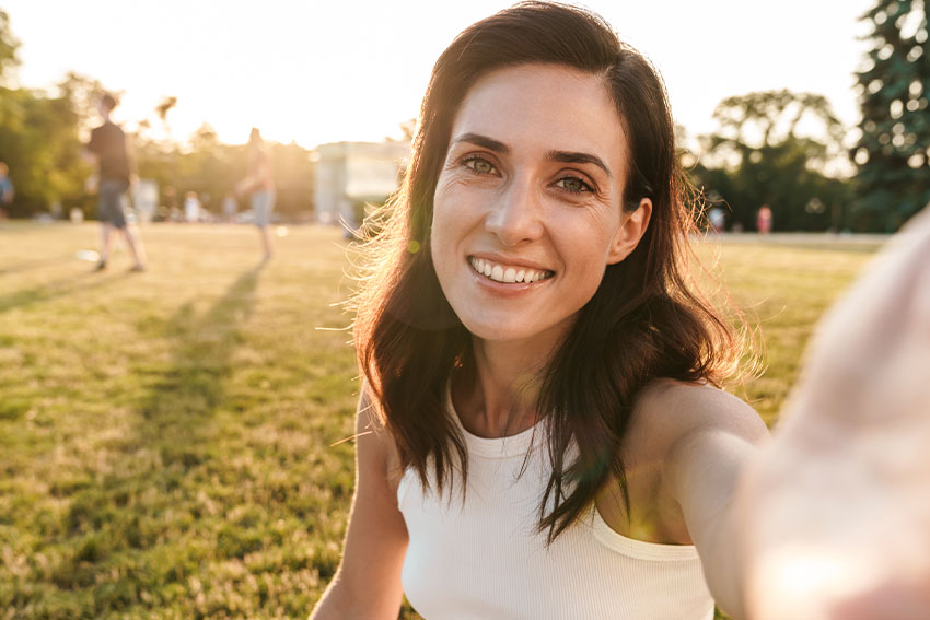 People-with-Dental-Implant-Enjoy-Higher-Quality-of-Life woman enjoying a fun day at the sunny park
