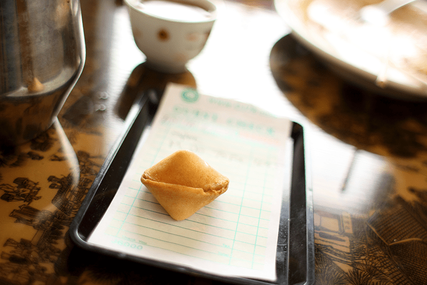 A Fortune Cookie resting on top of a bill at a Chinese restaurant. Inside might be your lucky numbers...and a smile makeover