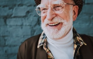 senior man with large glasses shows off his smile