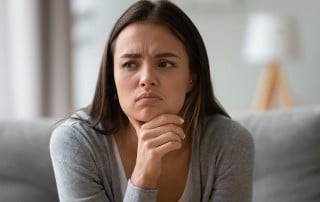 concerned woman sitting on her couch at home