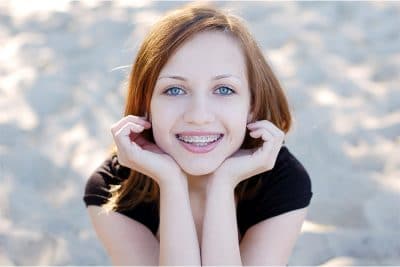Which-Orthodontic-Treatment-is-Right-For-You young red haired girl shows off her smile with metal braces