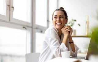 young woman sitting at her computer, drinking coffee during the day