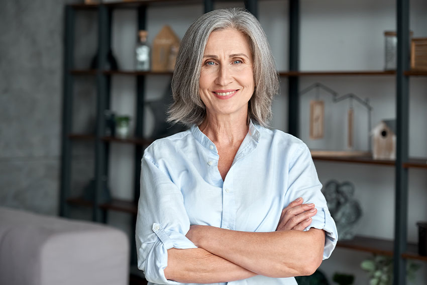 7-Reasons-Dental-Implants-Are-Better-Than-Dentures mature woman folding her arms, showing off her smile