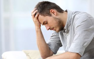 sad young man sits on the edge of his bed, disappointed.