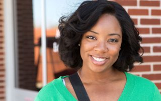 woman standing against brick background smiling