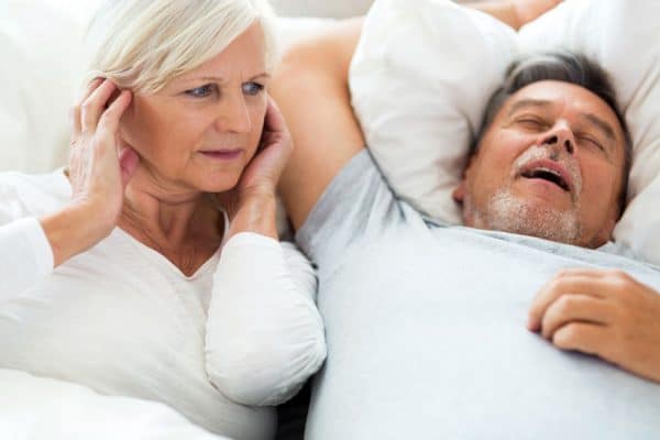 woman plugging her ears while partner snores